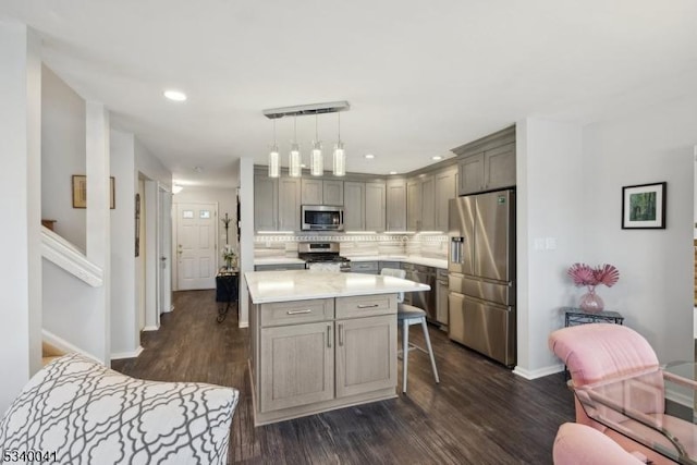 kitchen with dark wood-type flooring, gray cabinets, stainless steel appliances, light countertops, and backsplash