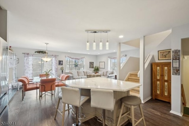 kitchen with light countertops, dark wood-style flooring, decorative light fixtures, and a kitchen bar