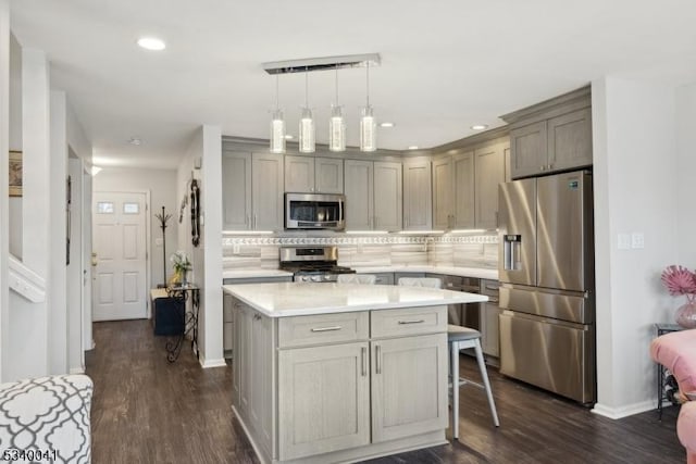 kitchen with dark wood finished floors, decorative backsplash, stainless steel appliances, and light countertops