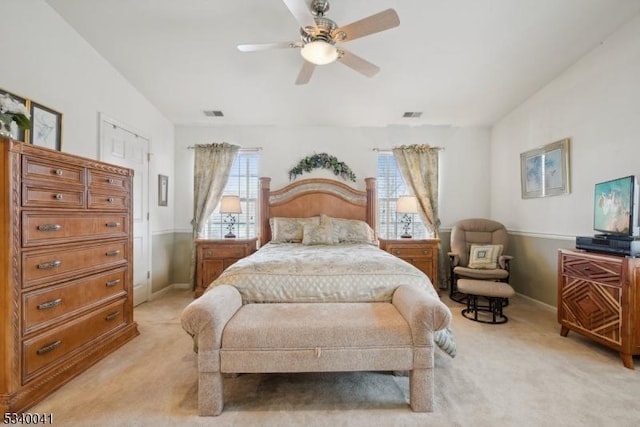 bedroom with light carpet, ceiling fan, visible vents, and baseboards