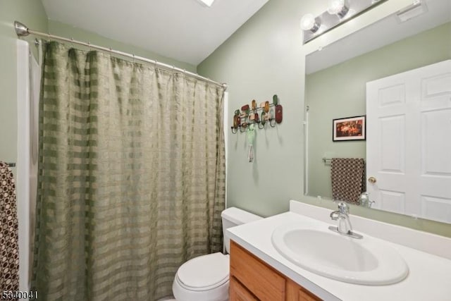 bathroom featuring toilet, curtained shower, and vanity