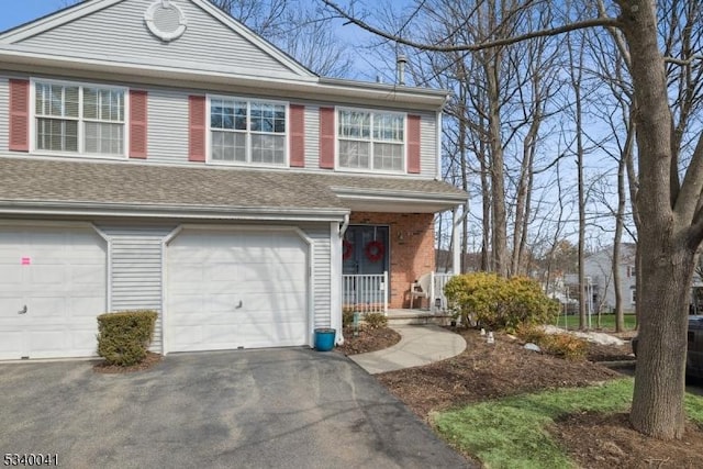 view of front of home with a garage, a porch, aphalt driveway, and roof with shingles