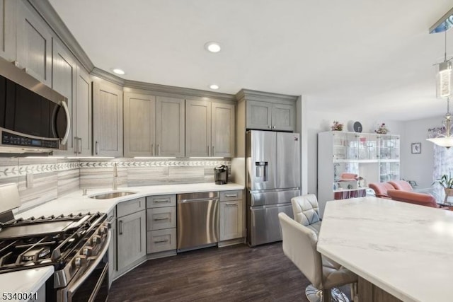 kitchen with stainless steel appliances, backsplash, gray cabinetry, dark wood-type flooring, and a sink