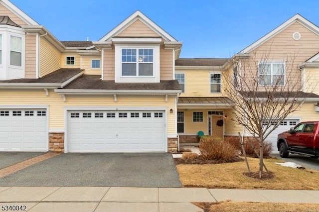 multi unit property featuring an attached garage, stone siding, and aphalt driveway