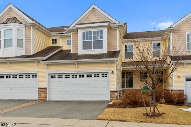 view of property featuring a garage, stone siding, and driveway