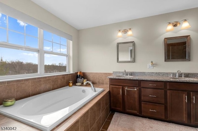 bathroom with double vanity, a garden tub, and a sink