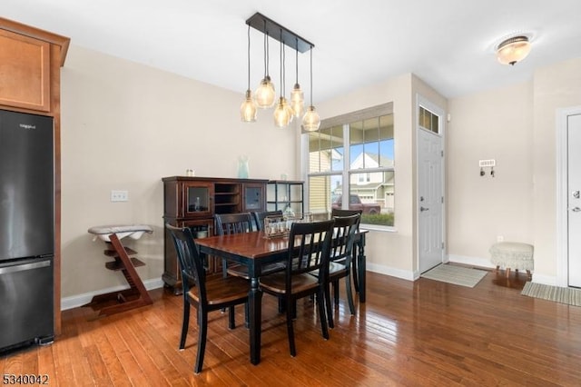 dining room with a notable chandelier, baseboards, and hardwood / wood-style flooring