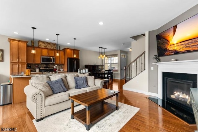 living room with a glass covered fireplace, light wood-style flooring, and recessed lighting