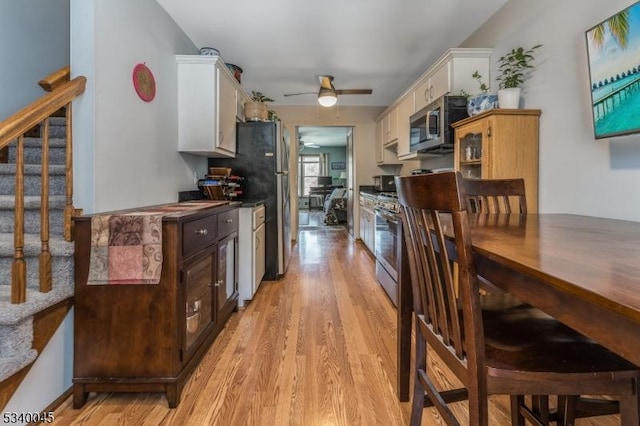 kitchen featuring light wood-type flooring, white cabinetry, dark brown cabinets, and stainless steel microwave