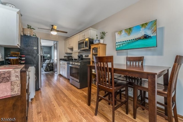 kitchen featuring white cabinets, light wood-type flooring, stainless steel appliances, and a ceiling fan