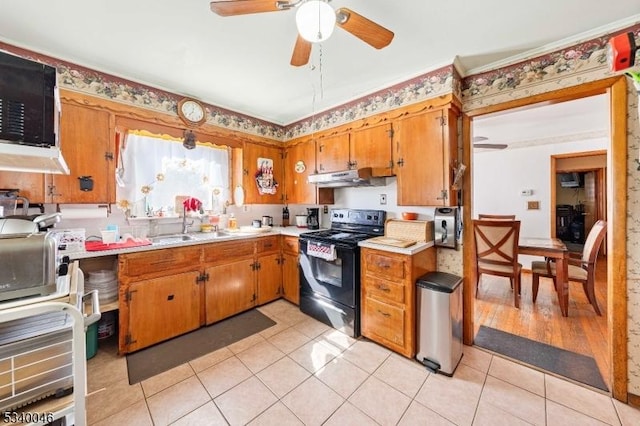 kitchen with black / electric stove, light tile patterned flooring, under cabinet range hood, a sink, and light countertops