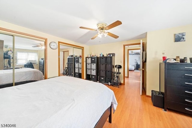 bedroom with light wood-type flooring, baseboards, a ceiling fan, and multiple closets