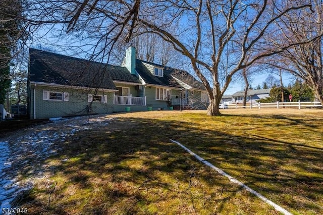 exterior space with a yard, a chimney, fence, and brick siding