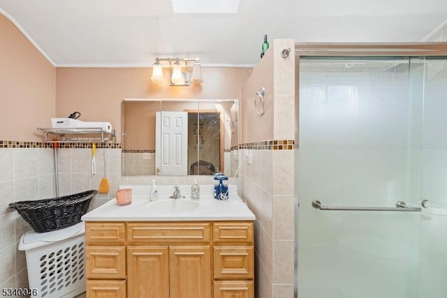 bathroom featuring a skylight, a shower stall, tile walls, and vanity