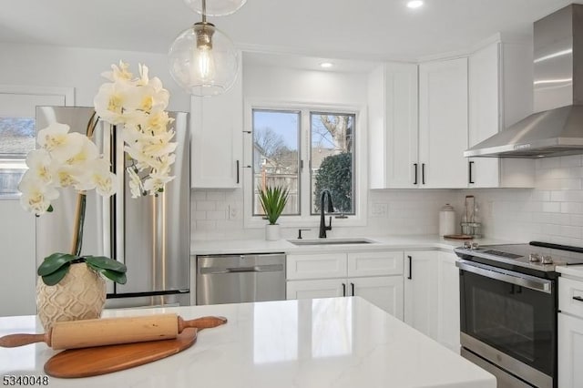 kitchen featuring appliances with stainless steel finishes, light countertops, a sink, and wall chimney exhaust hood