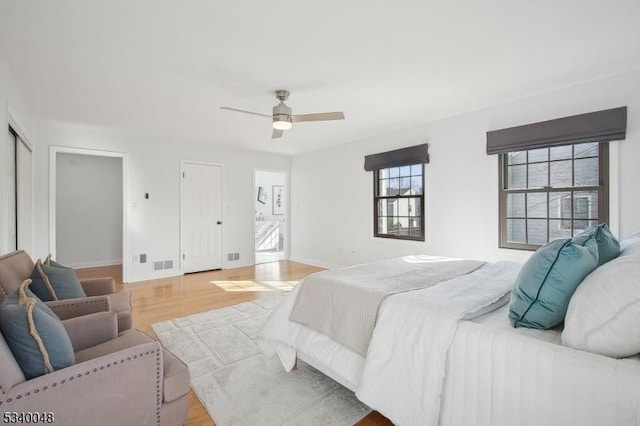 bedroom featuring light wood finished floors, baseboards, visible vents, and a ceiling fan