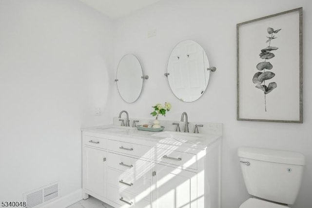 full bathroom with toilet, double vanity, a sink, and visible vents