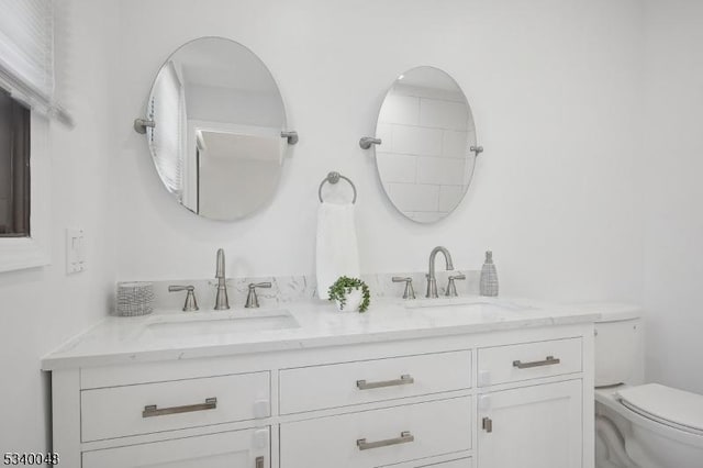 full bathroom with double vanity, toilet, and a sink