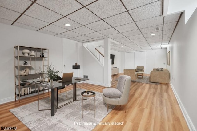 home office featuring wood finished floors, a paneled ceiling, and baseboards