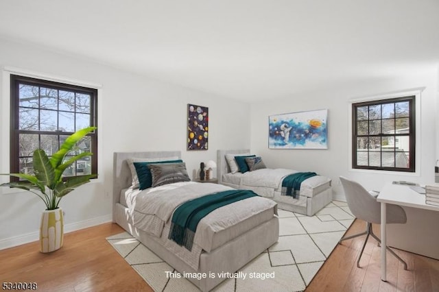 bedroom featuring light wood finished floors and baseboards