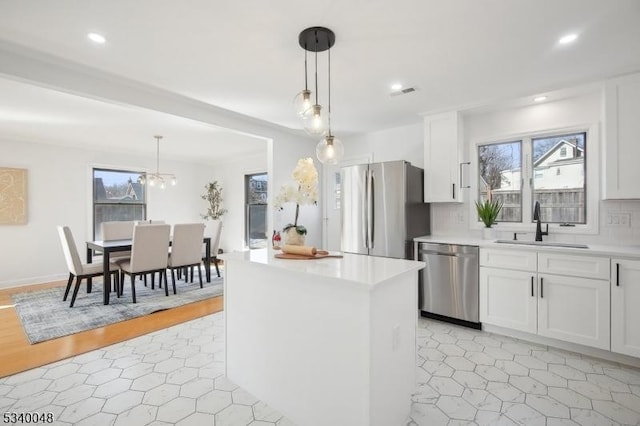 kitchen featuring appliances with stainless steel finishes, light countertops, decorative light fixtures, and white cabinetry