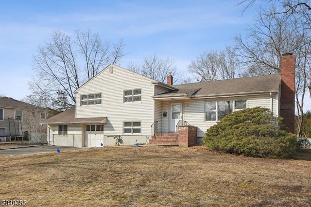 split level home with roof with shingles, a chimney, and a front yard