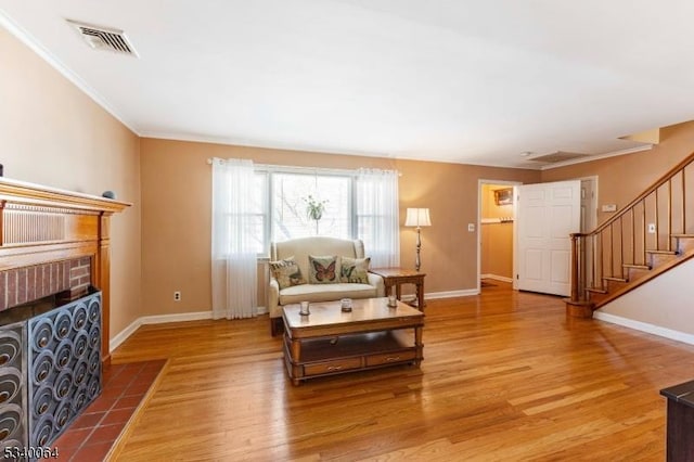 living room with ornamental molding, a fireplace, wood finished floors, and visible vents