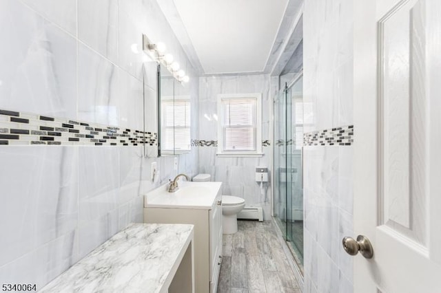 bathroom featuring tile walls, toilet, a baseboard heating unit, a shower stall, and vanity