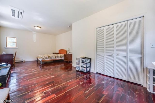 bedroom featuring a baseboard heating unit, a closet, visible vents, and dark wood-type flooring