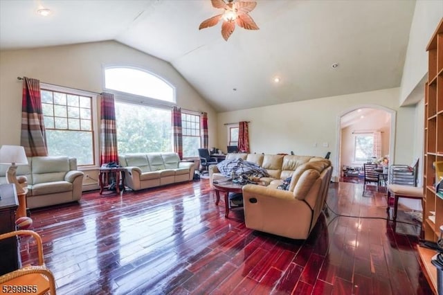 living room with dark wood-type flooring, arched walkways, plenty of natural light, and ceiling fan