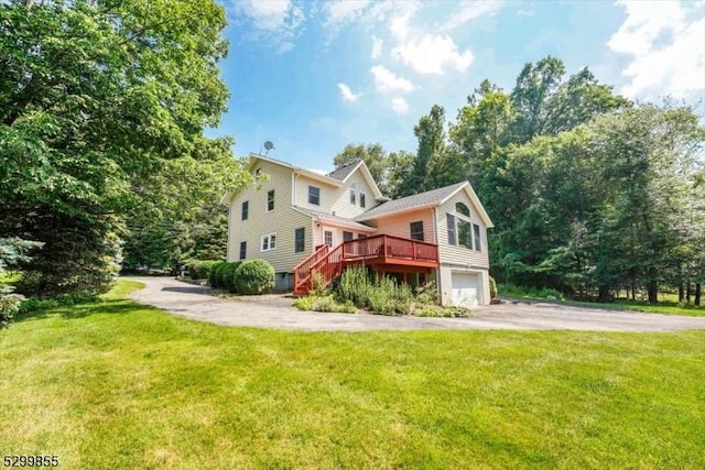 view of side of home with aphalt driveway, a garage, stairway, a lawn, and a wooden deck