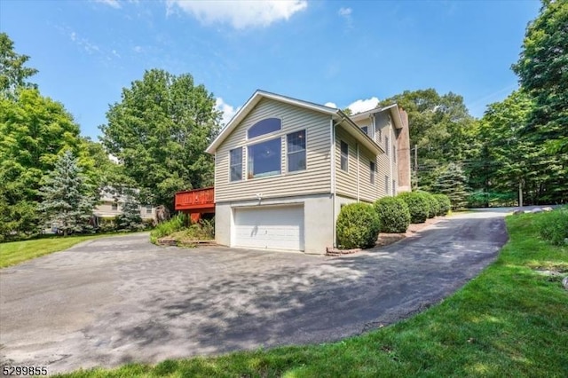 view of property exterior featuring a garage, aphalt driveway, and a wooden deck