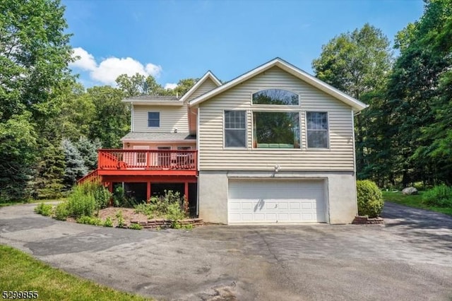 view of front facade featuring a garage, aphalt driveway, a deck, and stucco siding