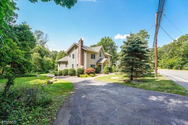 view of side of home featuring a chimney and a lawn