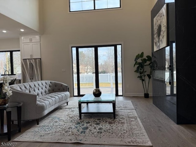 living room featuring baseboards, a towering ceiling, wood finished floors, french doors, and recessed lighting