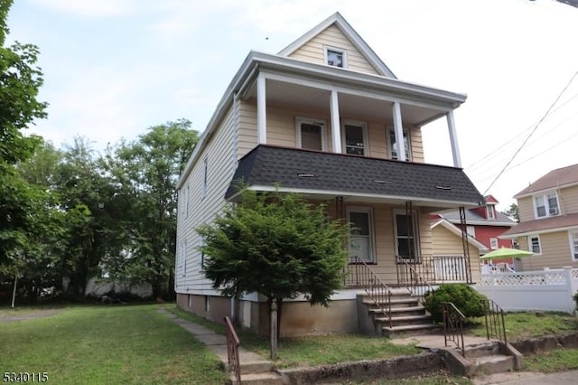 view of front of property with a porch, a front lawn, and a shingled roof