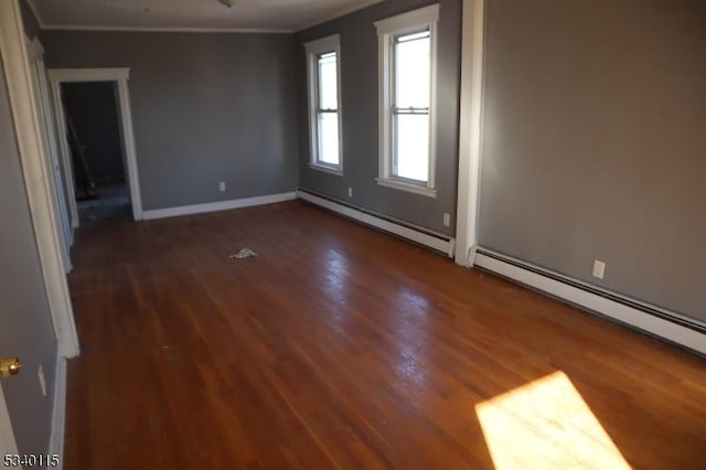 empty room with baseboards, dark wood-style floors, ornamental molding, baseboard heating, and a baseboard heating unit