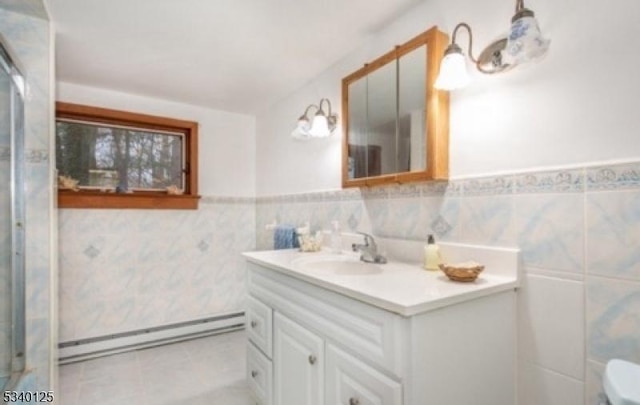 full bath featuring vanity, tile patterned flooring, wainscoting, tile walls, and a baseboard radiator