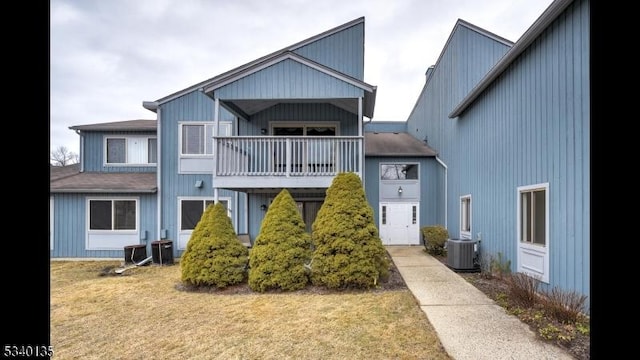 view of front of home featuring central air condition unit, a balcony, and a front lawn