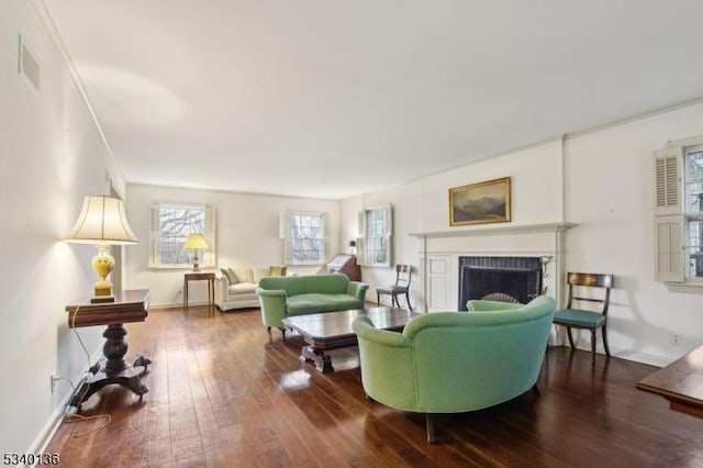 living area featuring wood-type flooring, visible vents, a fireplace, and baseboards