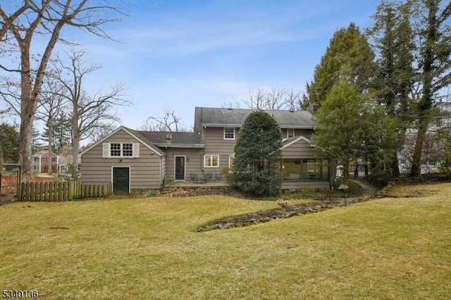 back of property featuring a sunroom, fence, and a yard