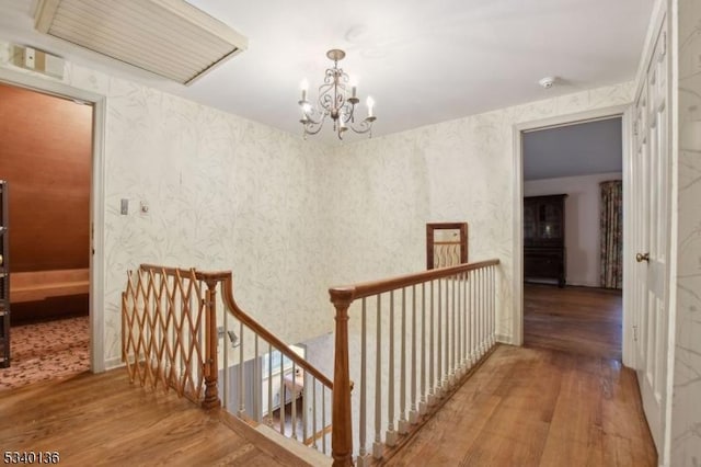 hallway with wood finished floors, an upstairs landing, and wallpapered walls