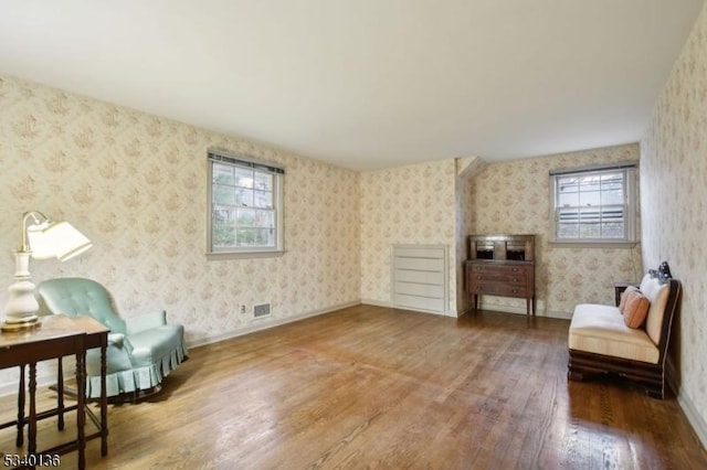 sitting room featuring baseboards, wood finished floors, and wallpapered walls