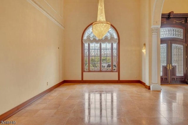 entryway with decorative columns, baseboards, an inviting chandelier, a high ceiling, and french doors