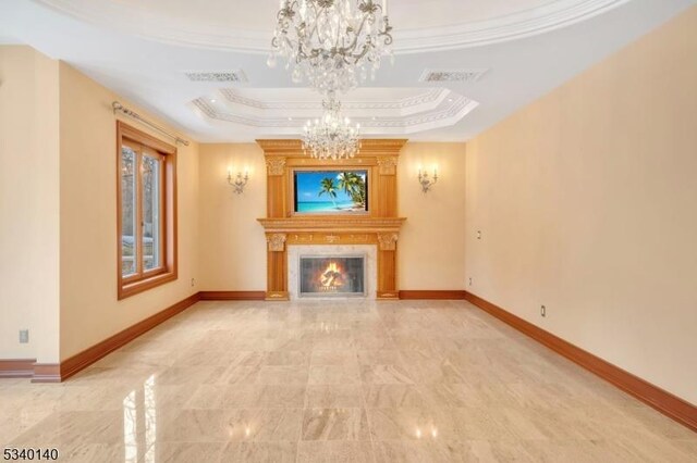 unfurnished living room with visible vents, baseboards, a glass covered fireplace, an inviting chandelier, and a tray ceiling