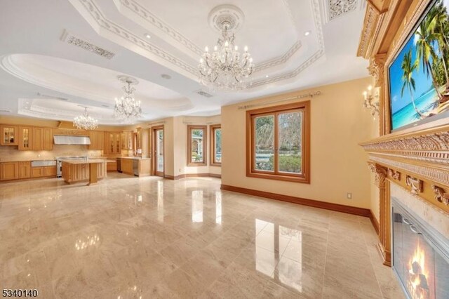 unfurnished living room with a fireplace, baseboards, ornamental molding, a raised ceiling, and an inviting chandelier