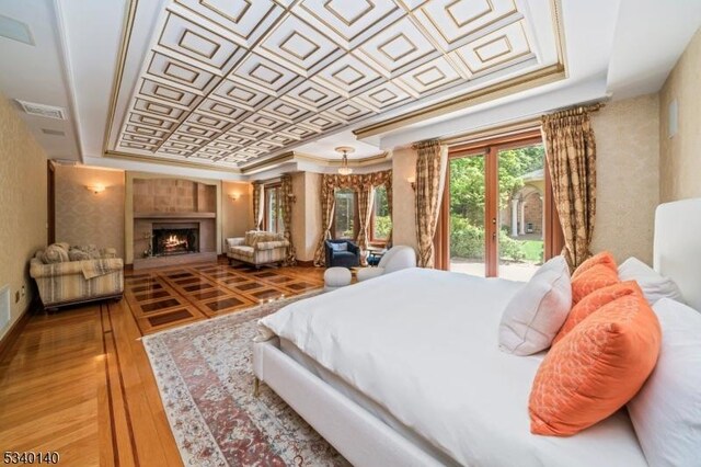 bedroom featuring a fireplace, a raised ceiling, an ornate ceiling, and crown molding