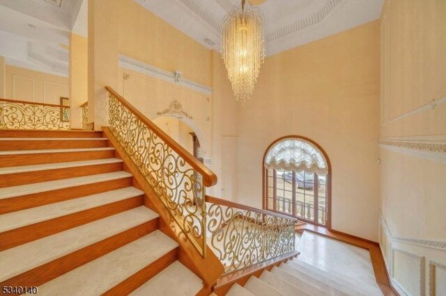 staircase featuring a towering ceiling and an inviting chandelier