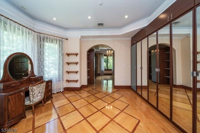 interior space featuring arched walkways, ornamental molding, a chandelier, and baseboards