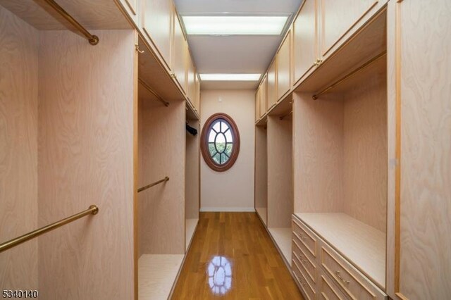 walk in closet with light wood-style floors